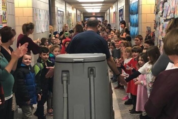 Custodian exits school hallway with humor while students and staff applaud pranks from employees who walked out with jokes.