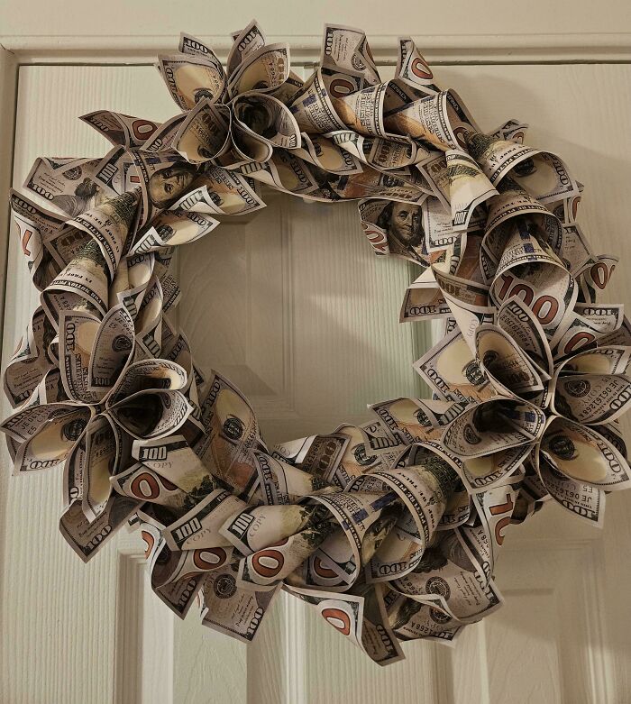 Wreath made of folded faux hundred-dollar bills hanging on a door, showcasing a playful and creative decoration.