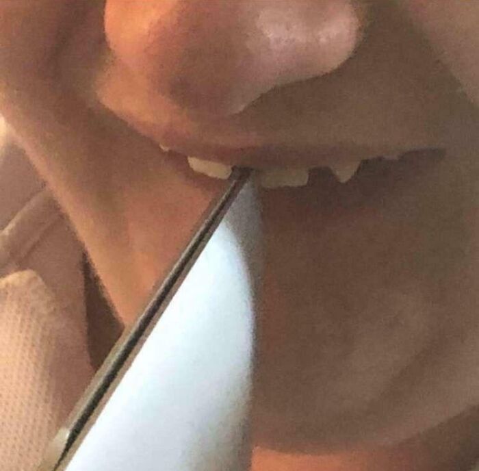 Close-up of a person perfectly aligning a knife edge with their teeth, showcasing precise alignment moments.
