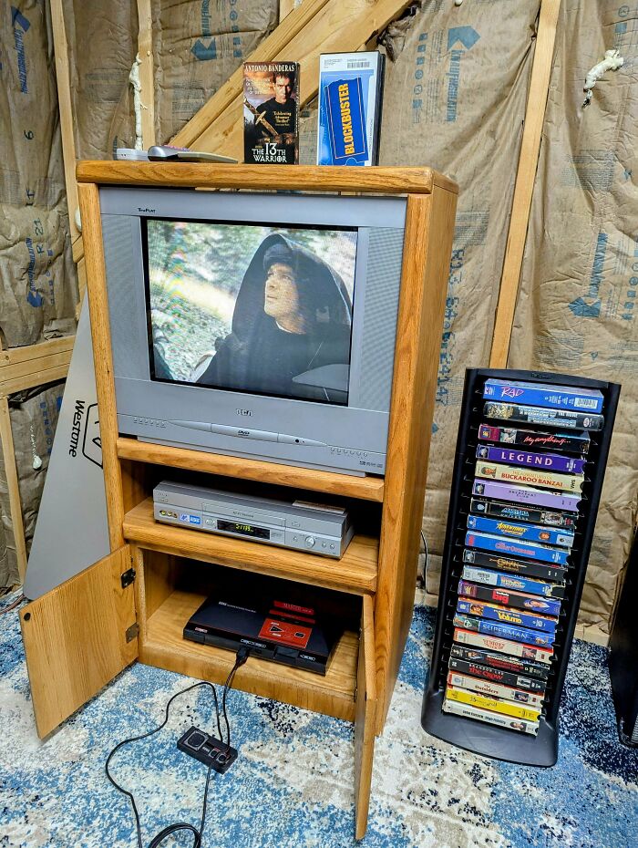 Vintage TV setup with a retro console, DVD player, and neatly aligned VHS tapes creating perfect nostalgic alignment.