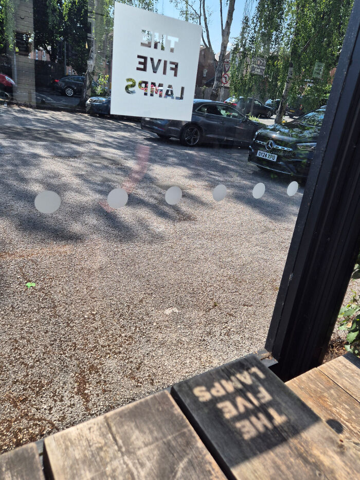 Reflection of the sign perfectly aligned on a wooden table through a glass window, showcasing things aligned perfectly.