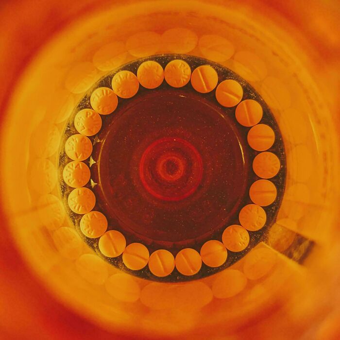 Perfectly aligned pills forming a neat circle inside an amber-colored bottle, showcasing precise things aligned arrangement.