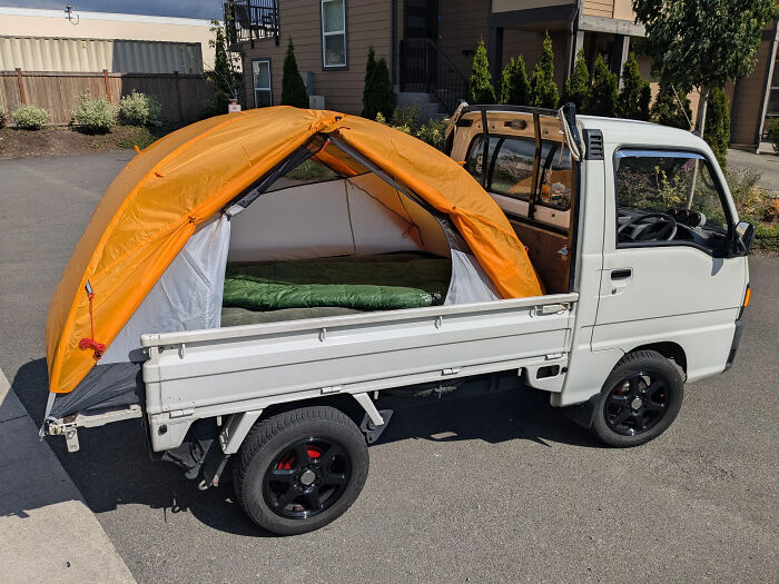 Mini truck with a perfectly aligned orange tent set up in the back, showcasing unusual and perfect alignment.