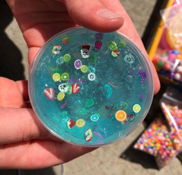 Child holding a container of blue slime with fruit-shaped beads, a popular kids toy during Black Friday deals.