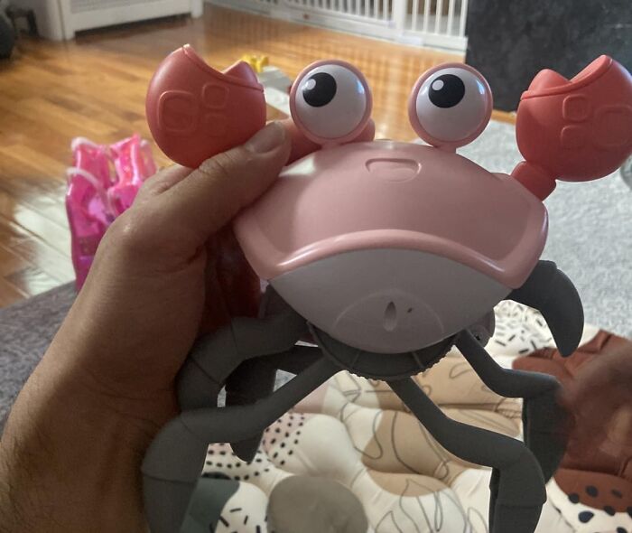 Hand holding a crab-shaped toy in a living room setting, showcasing Black Friday week deals on kids toys.