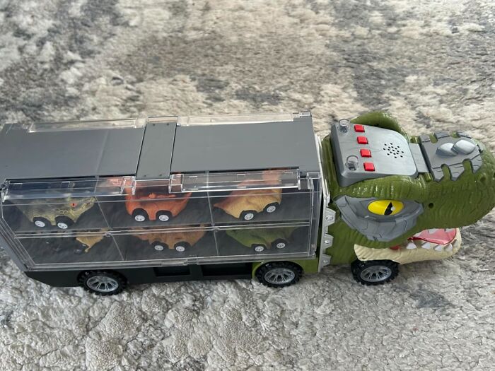 Toy crocodile truck carrying dinosaur figures on carpet, featured in Black Friday week deals on kids toys.