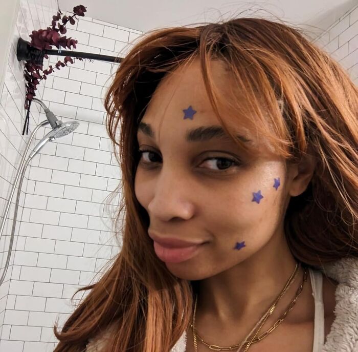 Woman with star stickers on her face smiling in a bathroom, illustrating ideas for Black Friday deals on stocking stuffers.