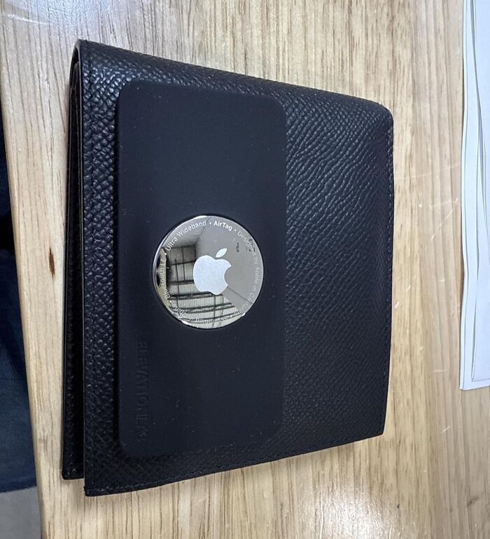 Black Friday deals on stocking stuffers featuring a sleek black wallet with an Apple AirTag attached on wood surface.