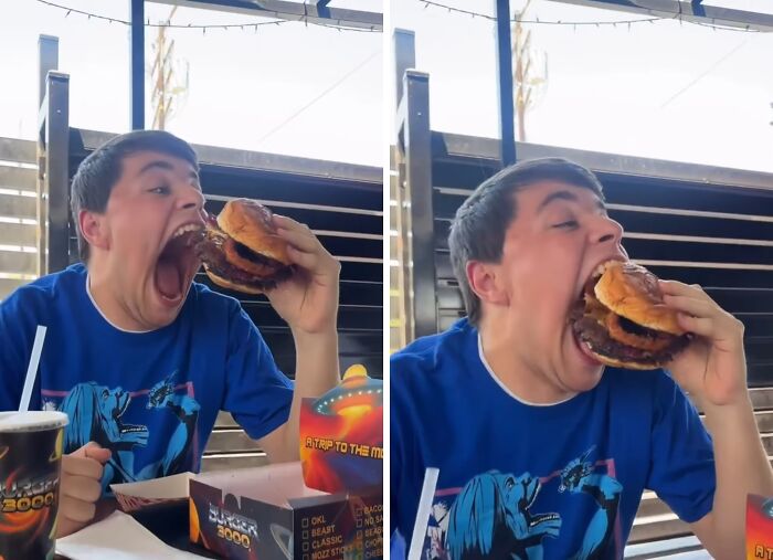 Young man wearing blue shirt taking a huge bite of a burger, showcasing a fun moment from Spill Now photos and facts.