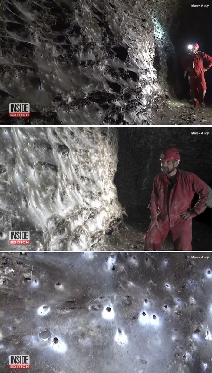 Caver in red suit exploring large spider web formations in a dark cave with glowing spiderholes.