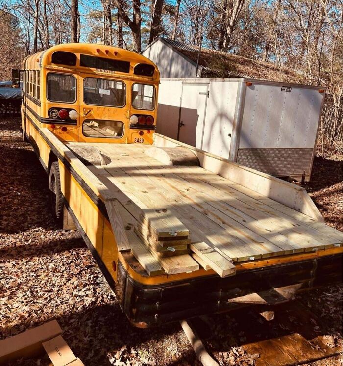 Redneck engineer's creative custom flatbed made from a repurposed school bus in an outdoor wooded area.