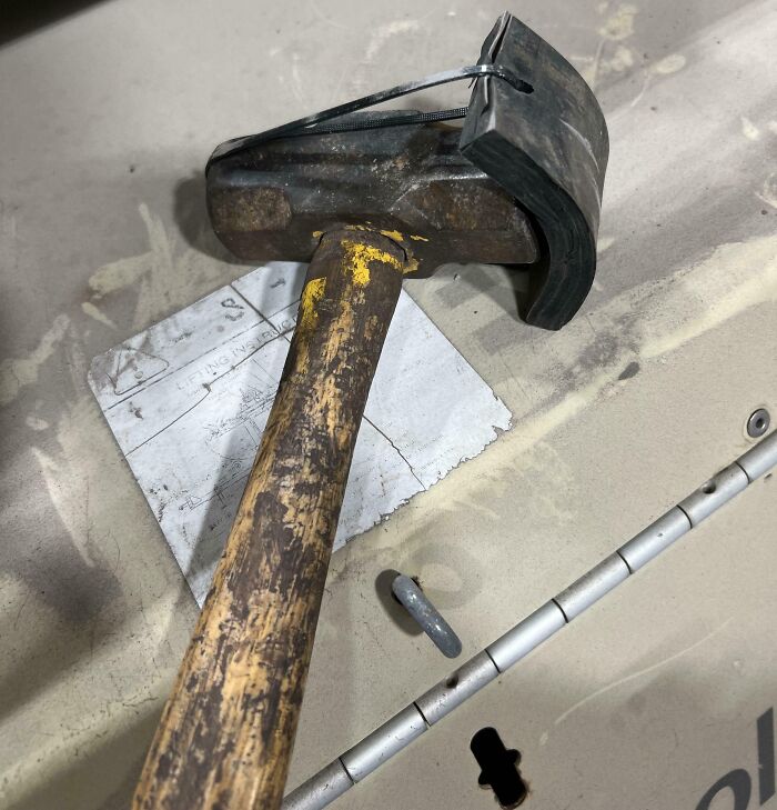 Rusty hammer with a makeshift rubber guard secured by a zip tie, a creative redneck engineering fix.