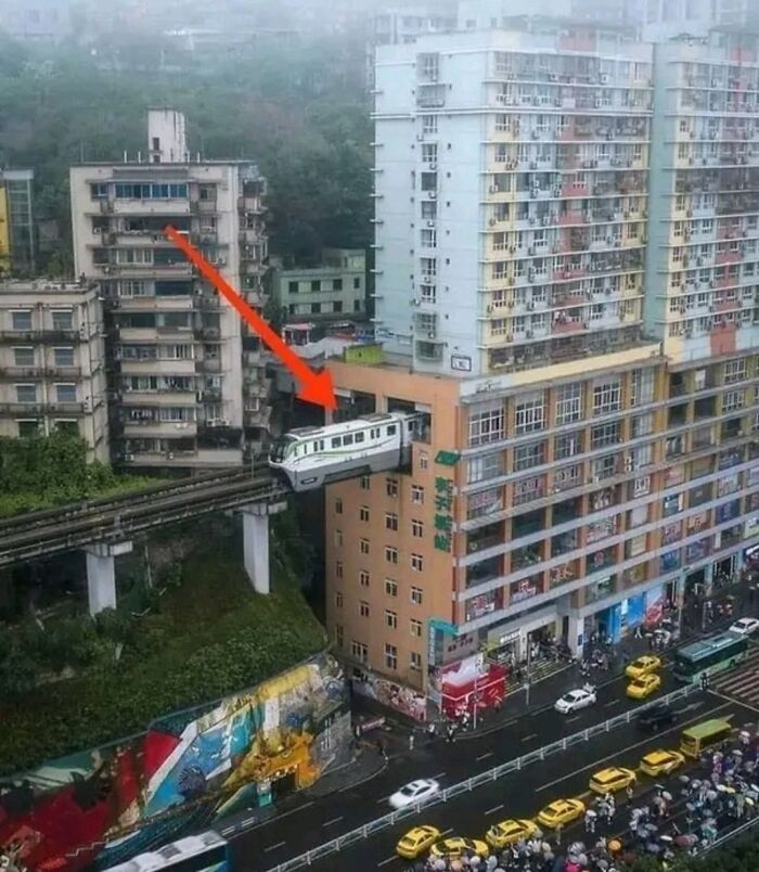 Train entering a building in a crowded city, illustrating strange facts and unusual scenes from our world.