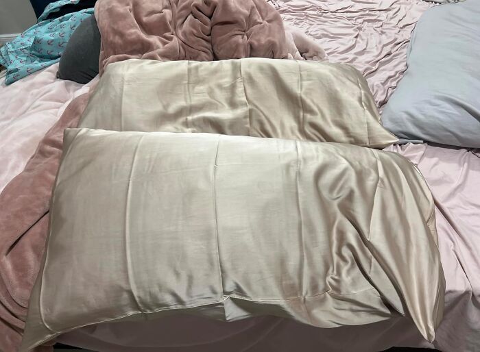 Two silk pillowcases on a bed with soft blankets, suitable as pretty and practical aesthetic gifts.