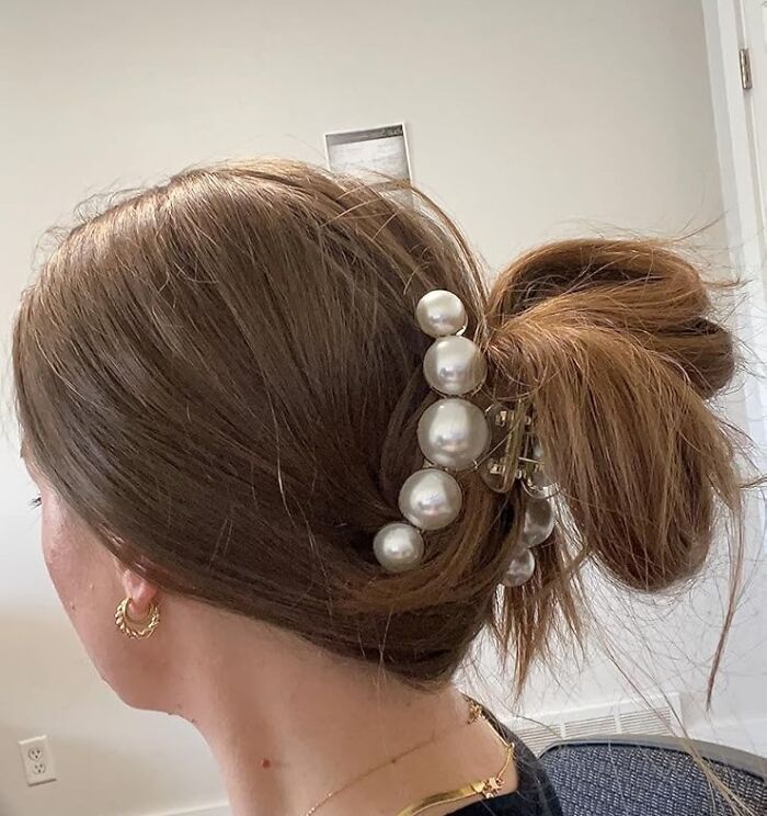 Woman with a pearl hair clip styled in a messy bun, showcasing pretty and practical aesthetic gifts for friends.