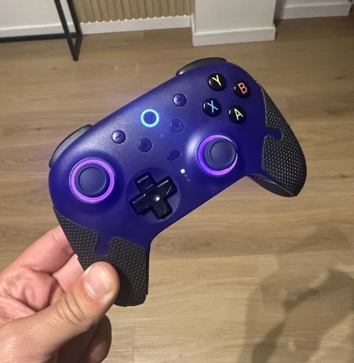 Hand holding a purple game controller with glowing buttons highlighting Black Friday deals for procrastinators.
