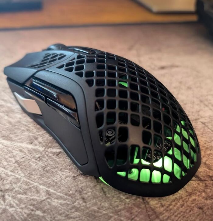 Black Friday deals on a black honeycomb gaming mouse with green lighting on a wooden surface.