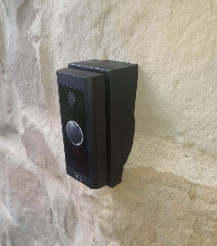 Ring doorbell perfectly aligned with irregular stone wall edges creating a visually satisfying fit and contrast.