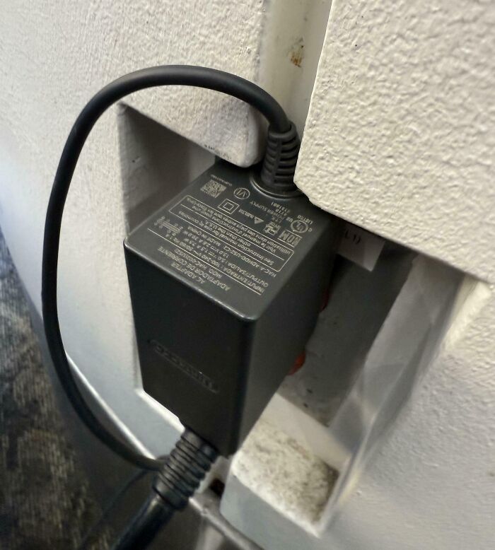 Power adapter perfectly aligned in a recessed wall outlet, illustrating times things aligned so perfectly to intrigue viewers.