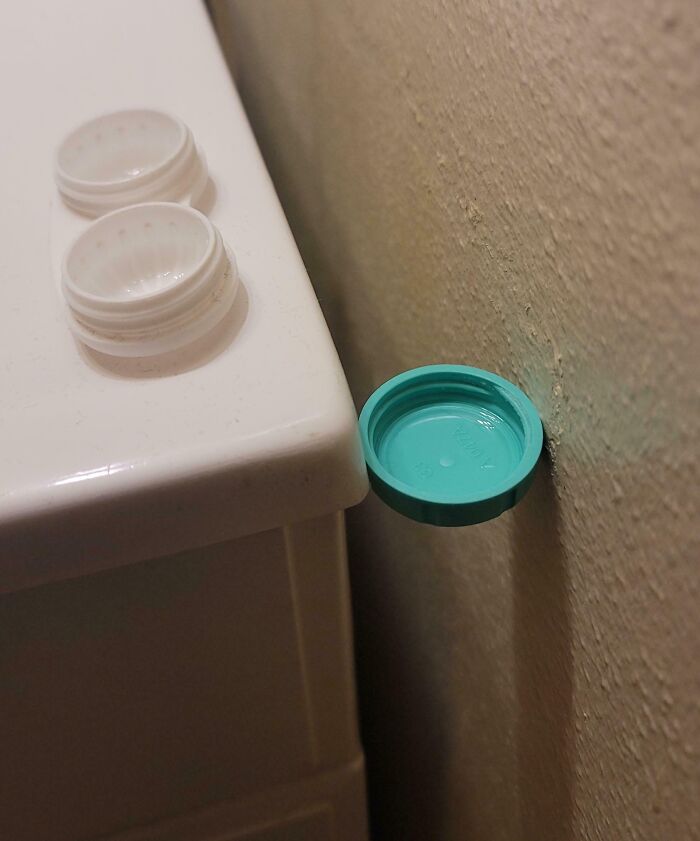 Plastic bottle caps aligned perfectly on edge and wall creating a visually satisfying moment of perfect alignment.