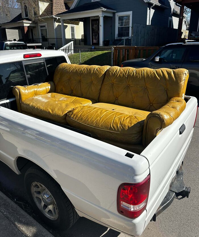Yellow vintage couch perfectly aligned in the bed of a white pickup truck, showcasing things aligned so perfectly.
