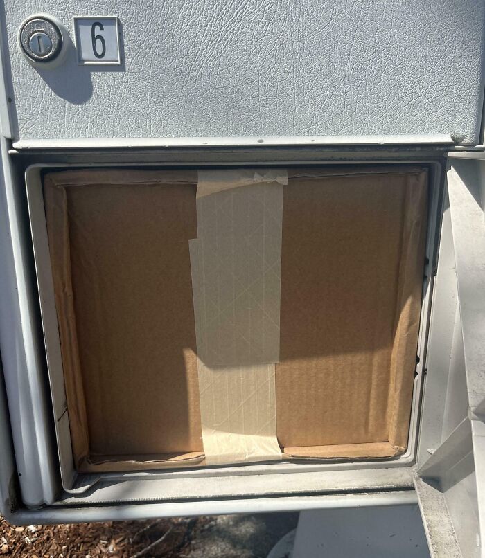 Mailbox door perfectly aligned with taped cardboard inside, showcasing things aligned so perfectly to intrigue the mind.