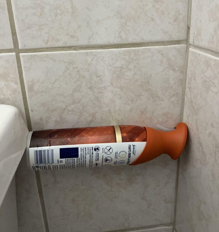 Spray bottle perfectly aligned and balanced horizontally between tiled bathroom walls, showcasing perfect alignment.