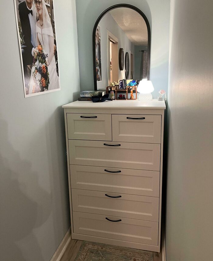 White dresser perfectly aligned in a narrow hallway with mirror and lamp, showcasing flawless alignment and organization.