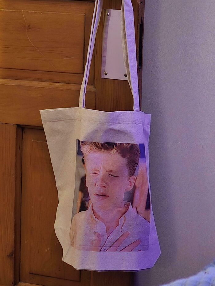 Tote bag hanging on a door with a printed image of a person squinting, illustrating things aligned perfectly.