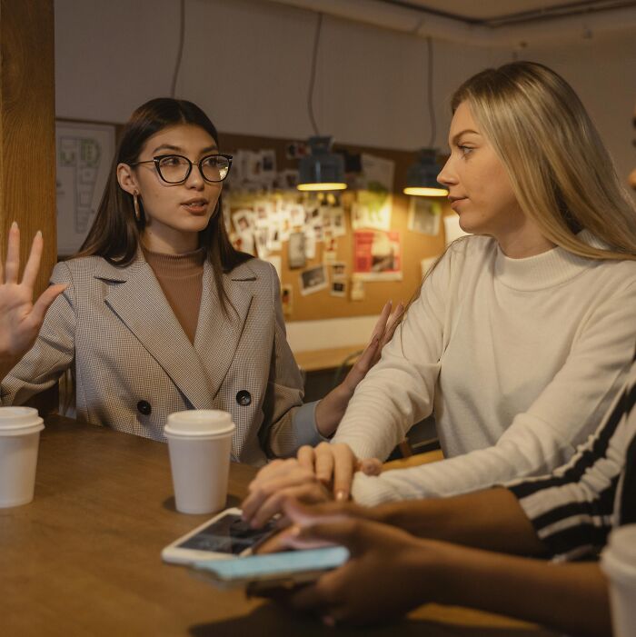 Three women having a relatable conversation over coffee, sharing funny and ridiculous moments together.