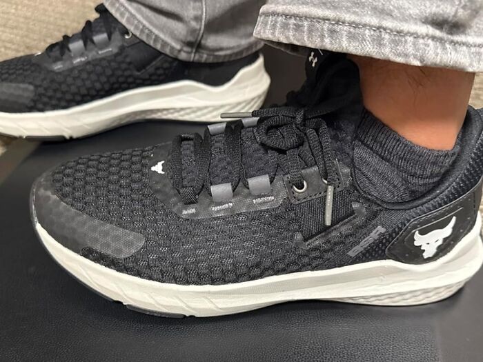 Black athletic shoes with white soles worn with gray jeans and black socks, showcasing Cyber Monday biggest steals for footwear deals.