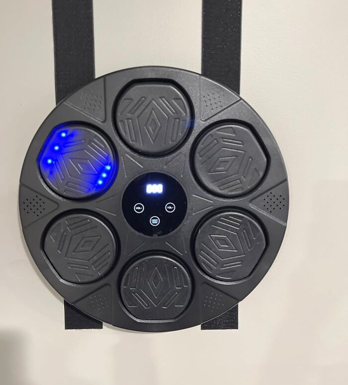 Black circular electronic drum pad with blue LED lights and digital display, featured in Cyber Monday tech deals.