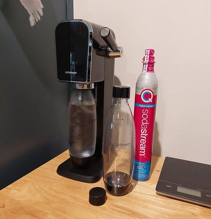 SodaStream sparkling water maker with bottles and CO2 canister on wooden table for Cyber Monday tech deals.