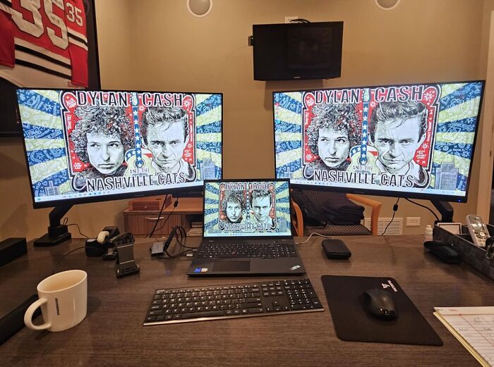 Home office setup with dual monitors and laptop displaying digital art, highlighting Cyber Monday tech deals for the weekend.