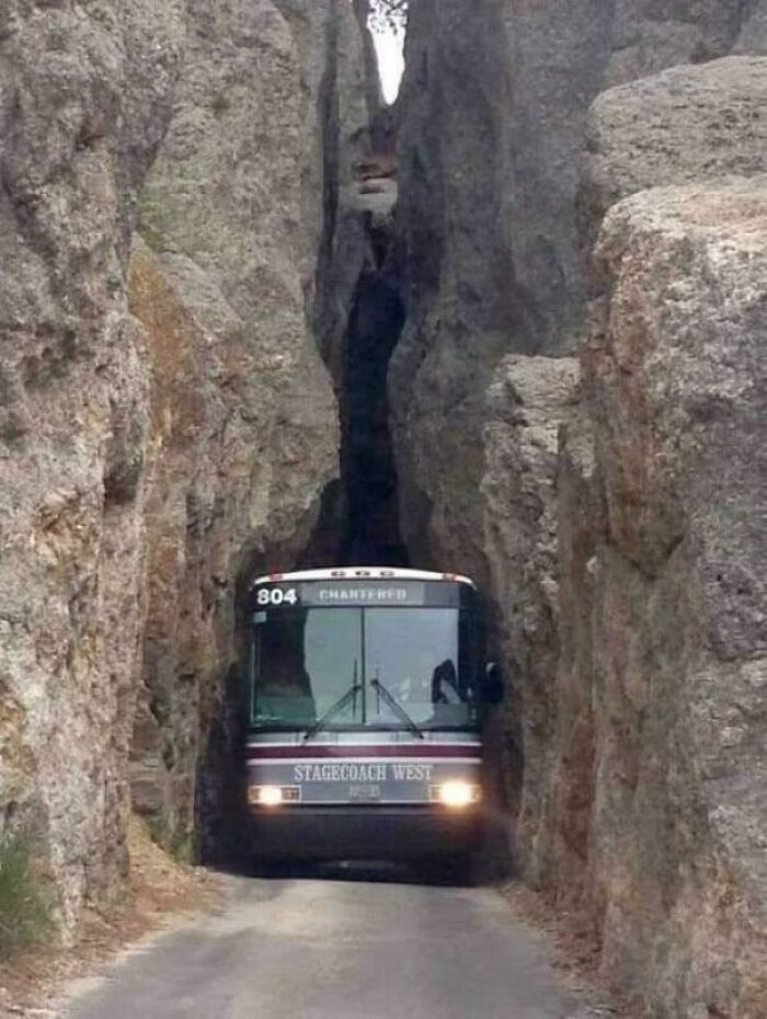 Bus navigating a narrow rocky passage, illustrating challenges in existence and reality within the universe.