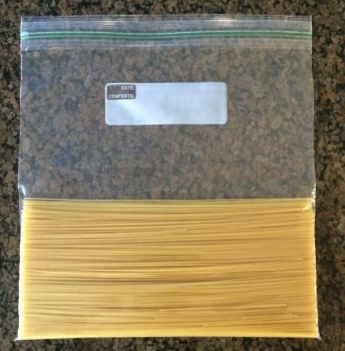Plastic bag filled with evenly aligned spaghetti noodles perfectly parallel on a granite countertop.