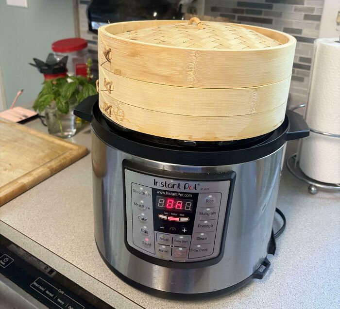 Bamboo steamer perfectly aligned on top of Instant Pot in modern kitchen setting.