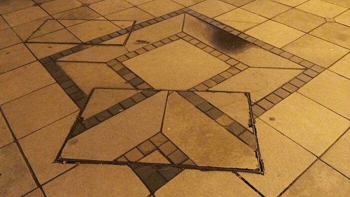 Uneven sidewalk tiles poorly installed, demonstrating bad workmanship and job mistakes with misaligned paving stones.