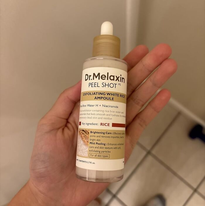 Hand holding Dr. Melaxin Peel Shot exfoliating white rice ampoule, a popular Cyber Monday deals skincare product.