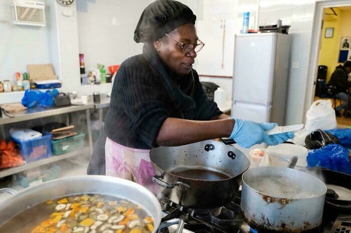 Woman cooking in a kitchen, showcasing strength and diversity in a portrait that captures overlooked human beauty.