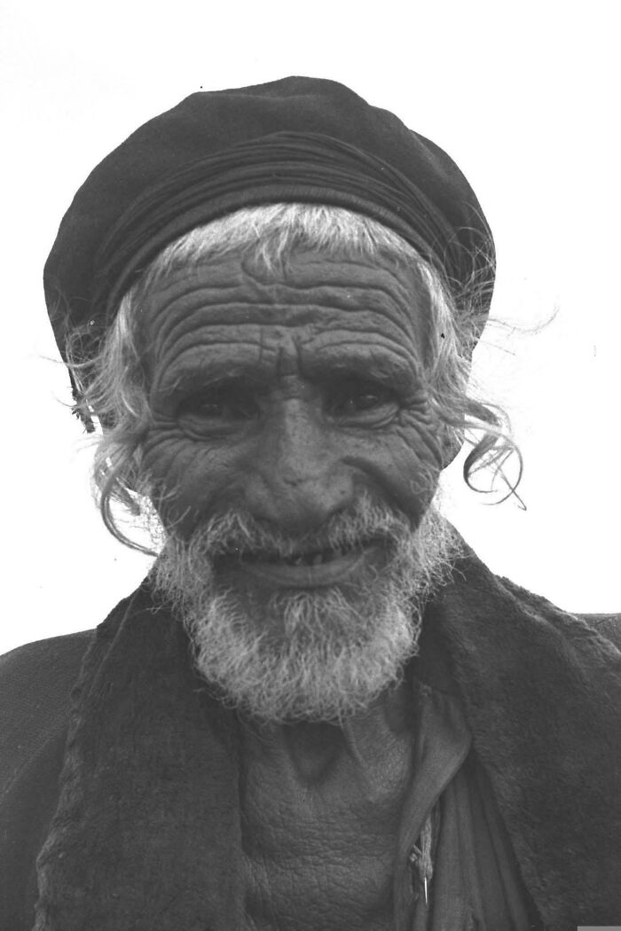 Elderly man with deep wrinkles and a beard, wearing a hat, capturing the beauty and strength of overlooked humans.