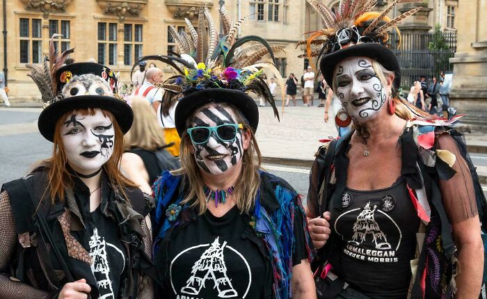Three people with face paint and feathered hats showcasing the strength and diversity of humans often overlooked in portraits