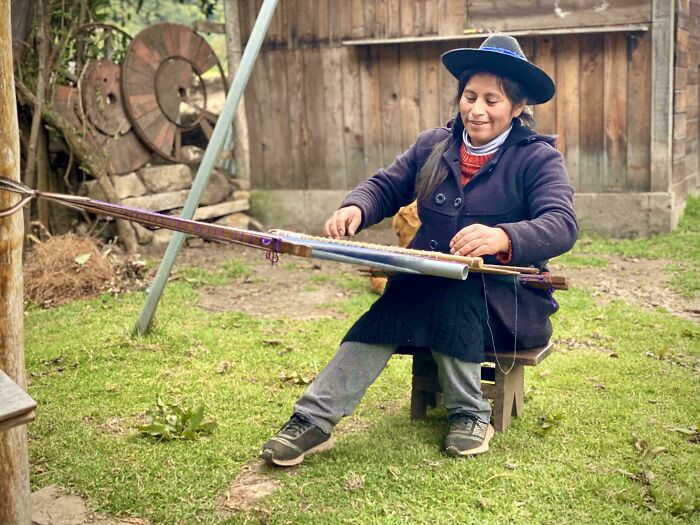 Woman wearing a hat playing a traditional string instrument outdoors, capturing the strength and diversity of humans