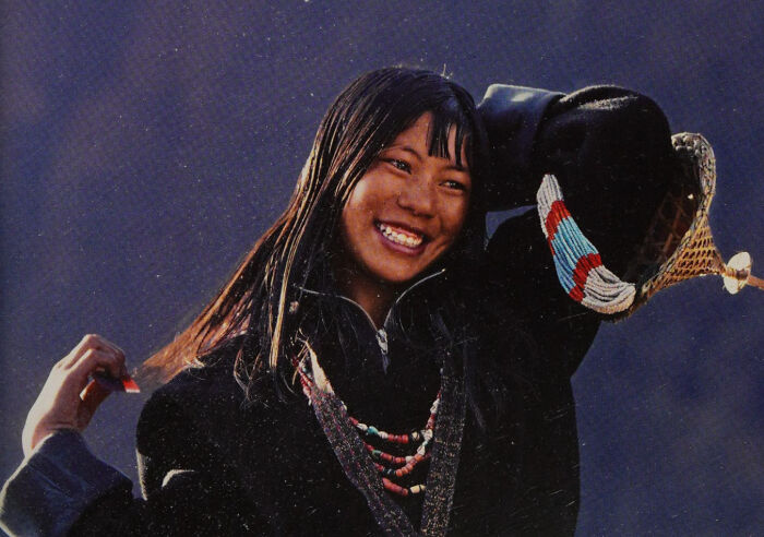 Young woman smiling wearing traditional attire, a portrait capturing human beauty, strength, and diversity often overlooked.