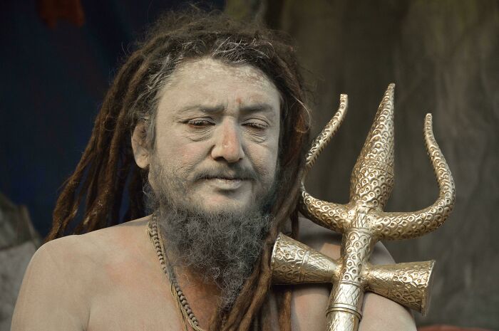 Portrait of a man with dreadlocks and facial hair holding a detailed trident, showcasing human beauty, strength, and diversity.