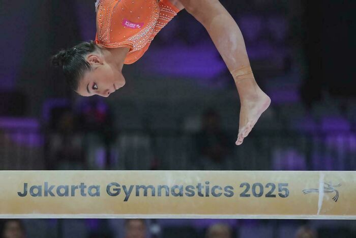Gymnast performing a mid-air routine on the balance beam, capturing strength and beauty in human movement.