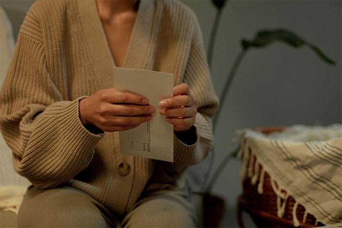 Woman in a cozy sweater holding a letter, illustrating a mom preventing solicitor contact about grandma’s inheritance. Woman in a cozy sweater holding a letter, illustrating a mom preventing solicitor contact about grandma’s inheritance.