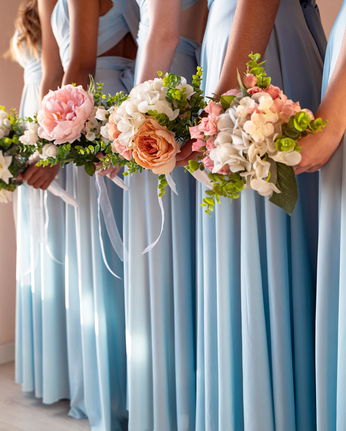 Bridesmaids in blue dresses holding floral bouquets, related to woman refusing to pay for altered borrowed dress.