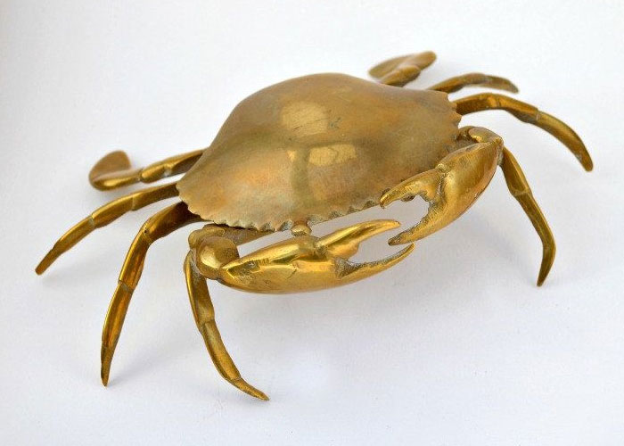 Brass crab sculpture found among fascinating items hidden in the walls of old homes, showcasing unique wall discoveries.