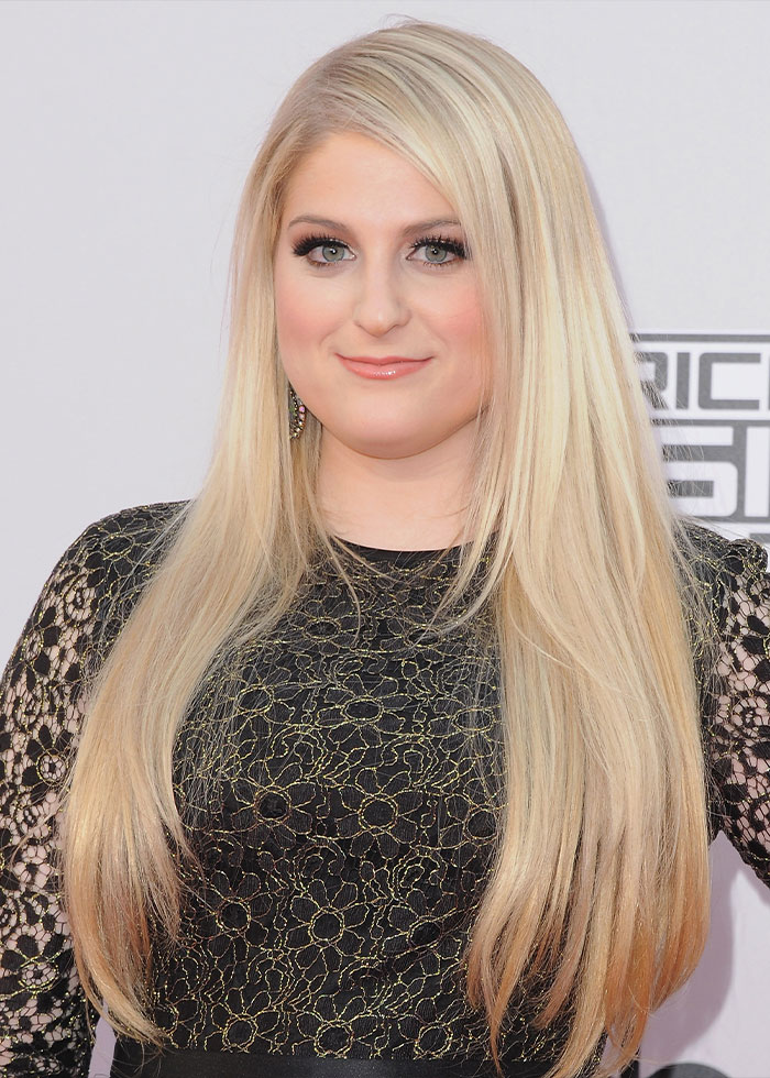 Meghan Trainor with long blonde hair and black lace dress, highlighting her new look that fans find hilarious.